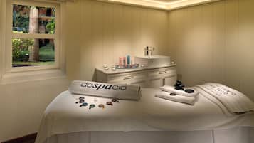 Relax in a serene space with a view of lush greenery, featuring a massage table, vanity, and calming ambiance.