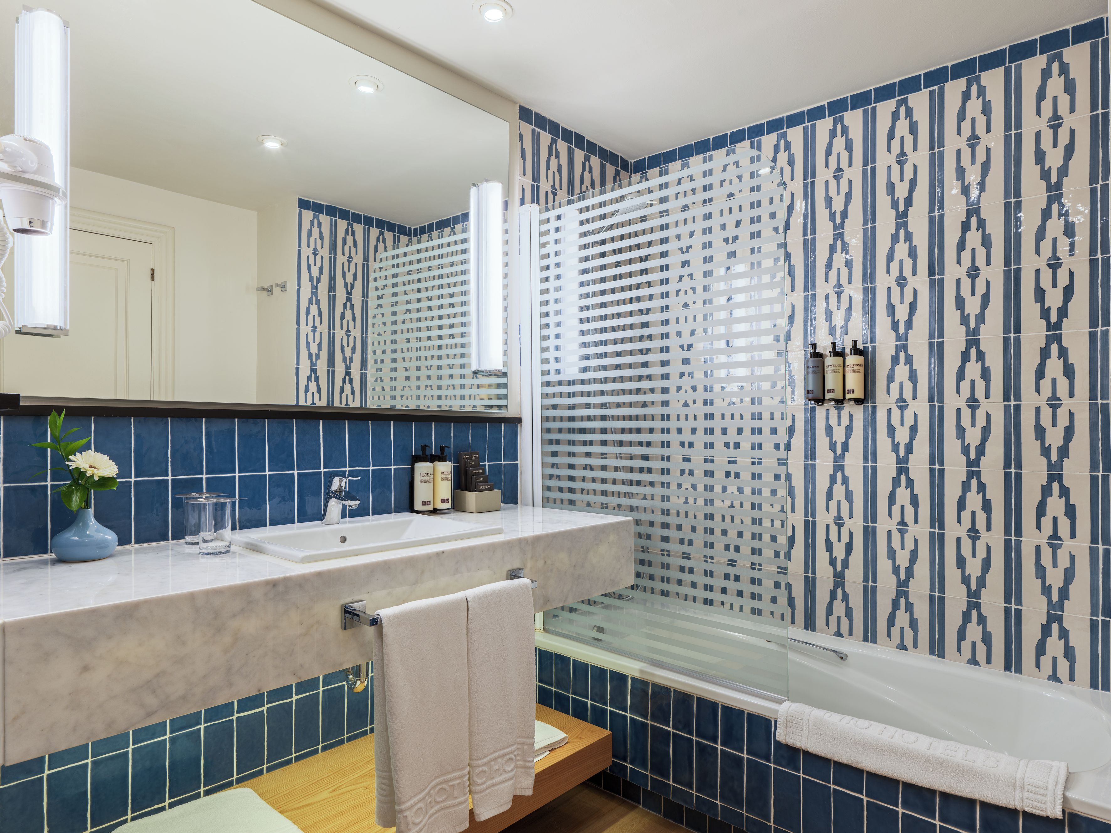 A bathroom with a large mirror, a sink, a glass shower enclosure, and a bathtub.