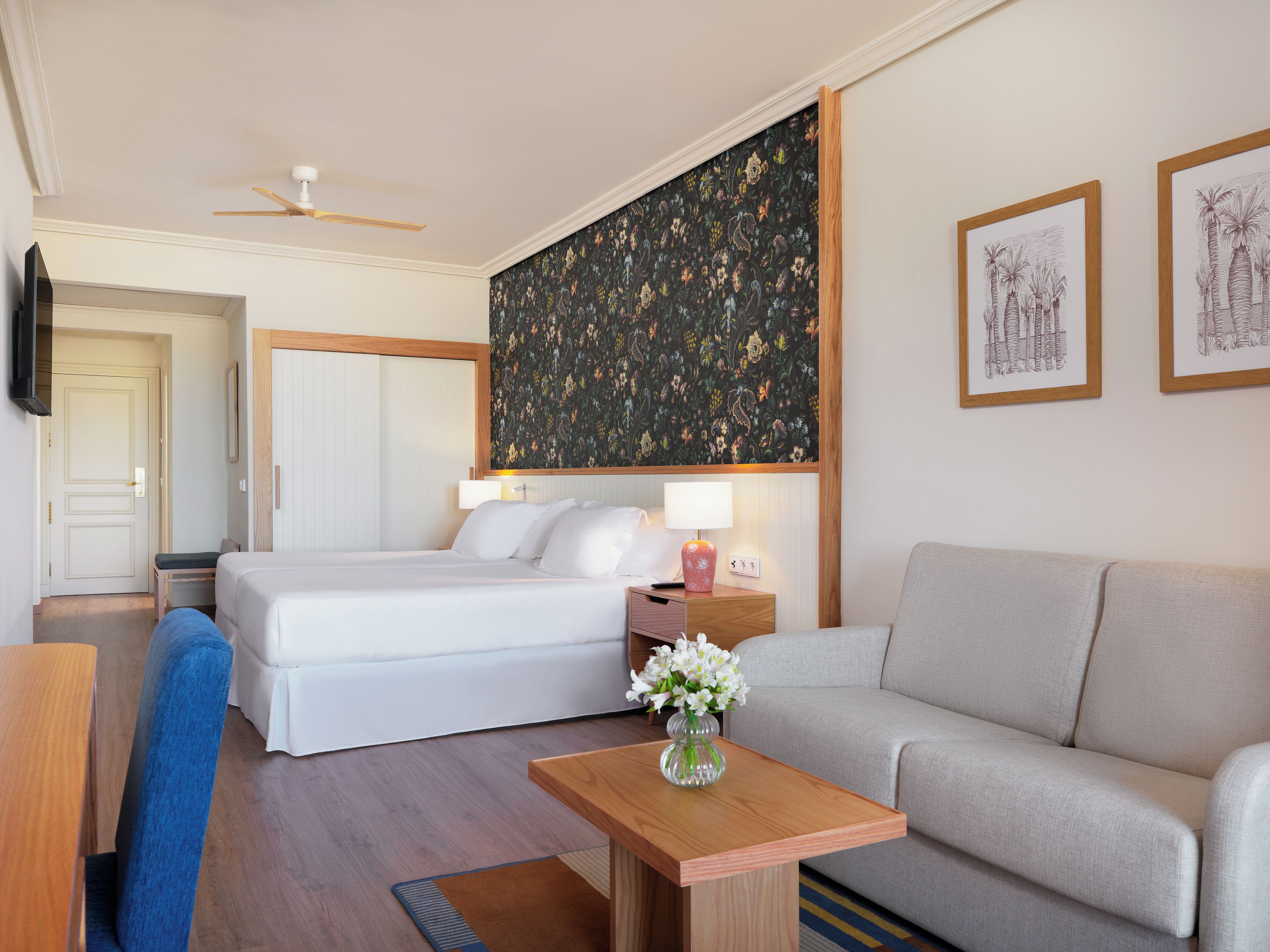 Habitación de hotel con cama, sofá, escritorio y televisor.