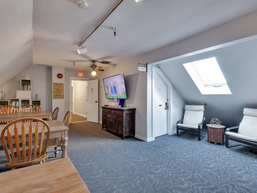 A room with a dining area, a TV, a ceiling fan, and a skylight.
