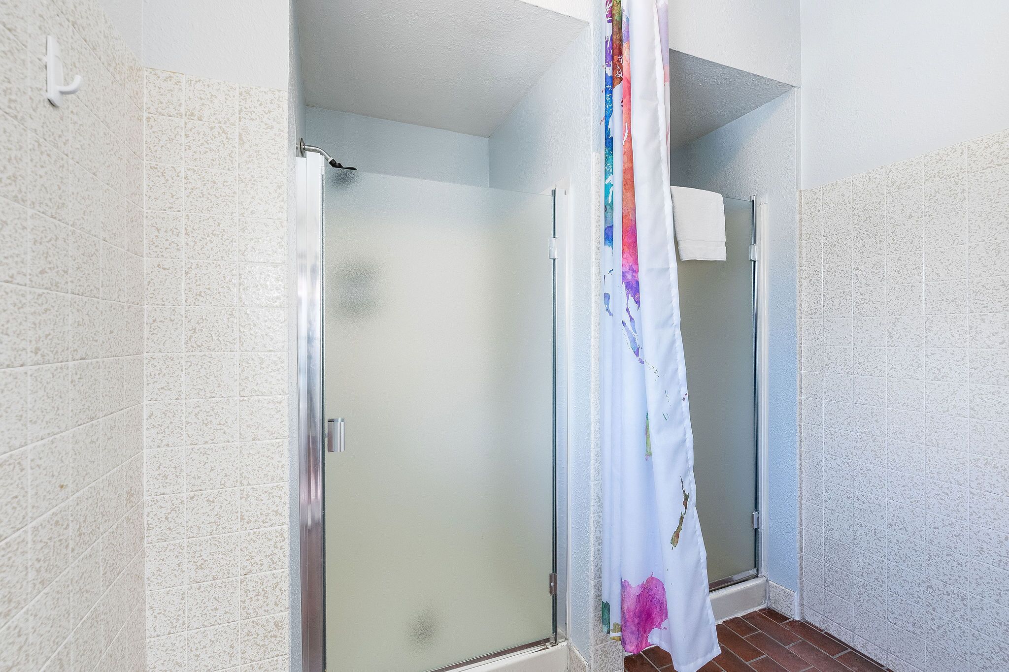 Un baño con ducha, paredes de azulejos y puerta de vidrio.