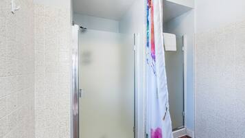 Un baño con ducha, paredes de azulejos y puerta de vidrio.