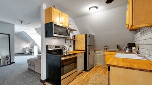 Cocina moderna con microondas, estufa, horno y refrigerador. Cuenta con una encimera de madera y un lavamanos.