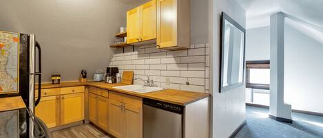 A modern kitchen with wooden cabinets, a dishwasher, and a map on the wall.