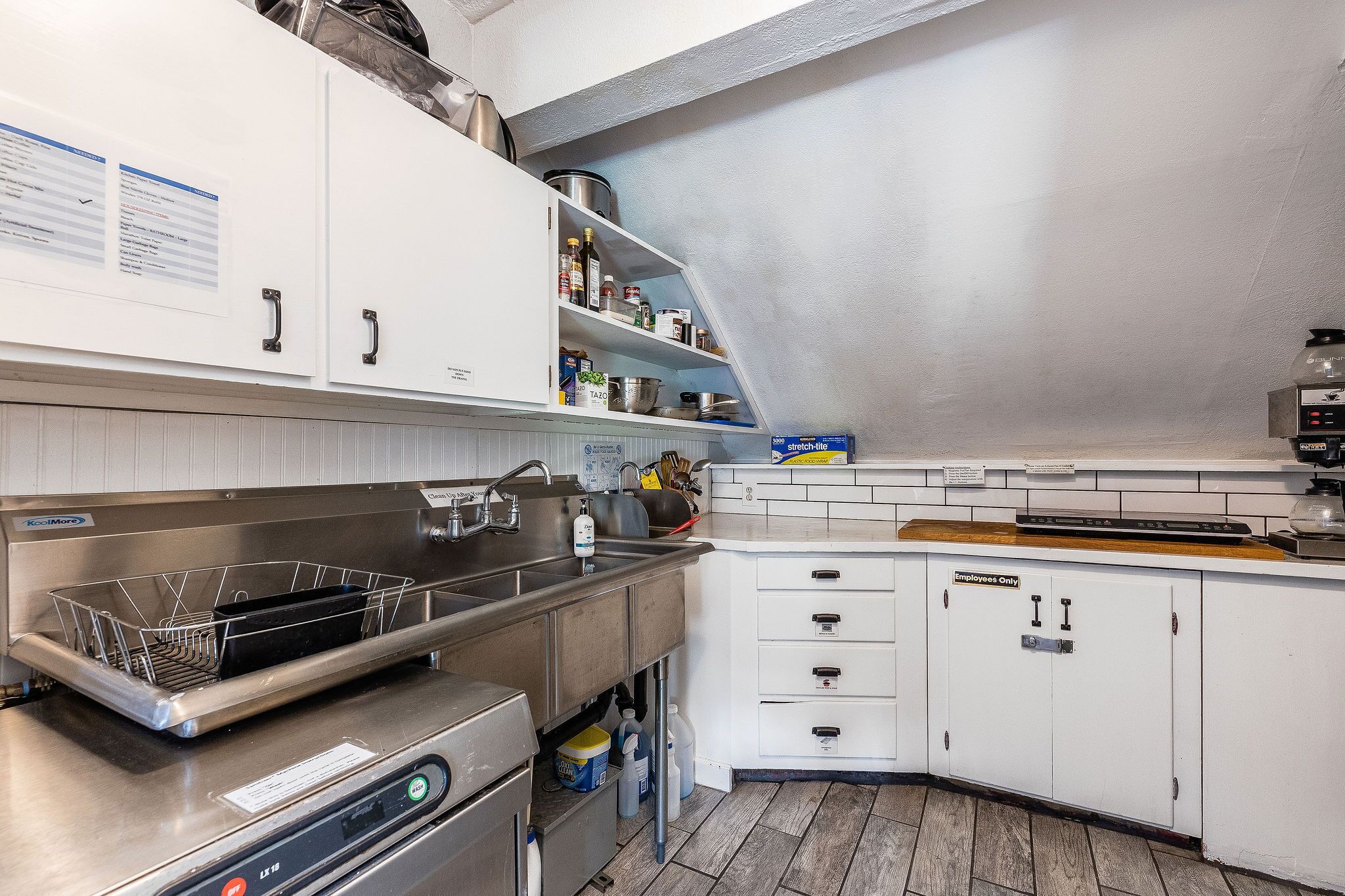 A modern kitchen with white cabinets, stainless steel appliances, and a wooden countertop.