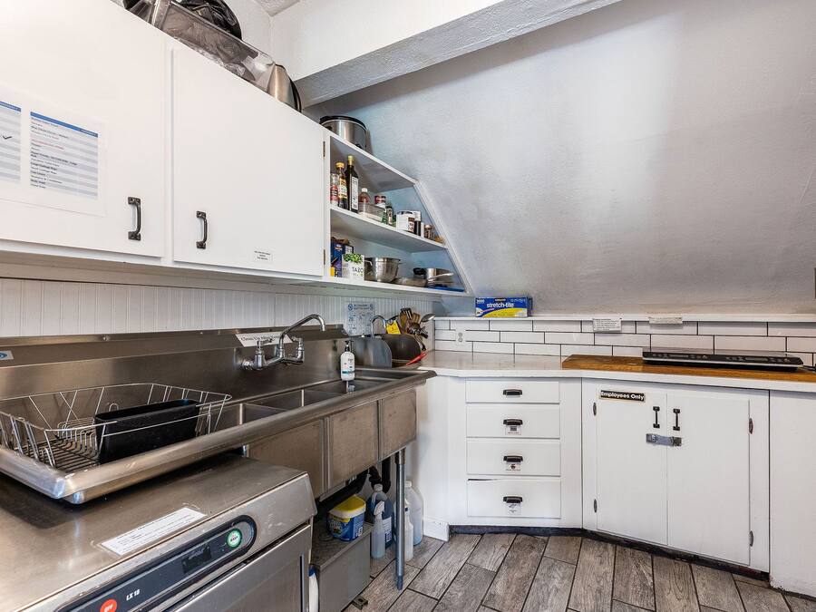 Una cucina moderna con mobili bianchi, elettrodomestici in acciaio inossidabile e un piano di lavoro in legno.