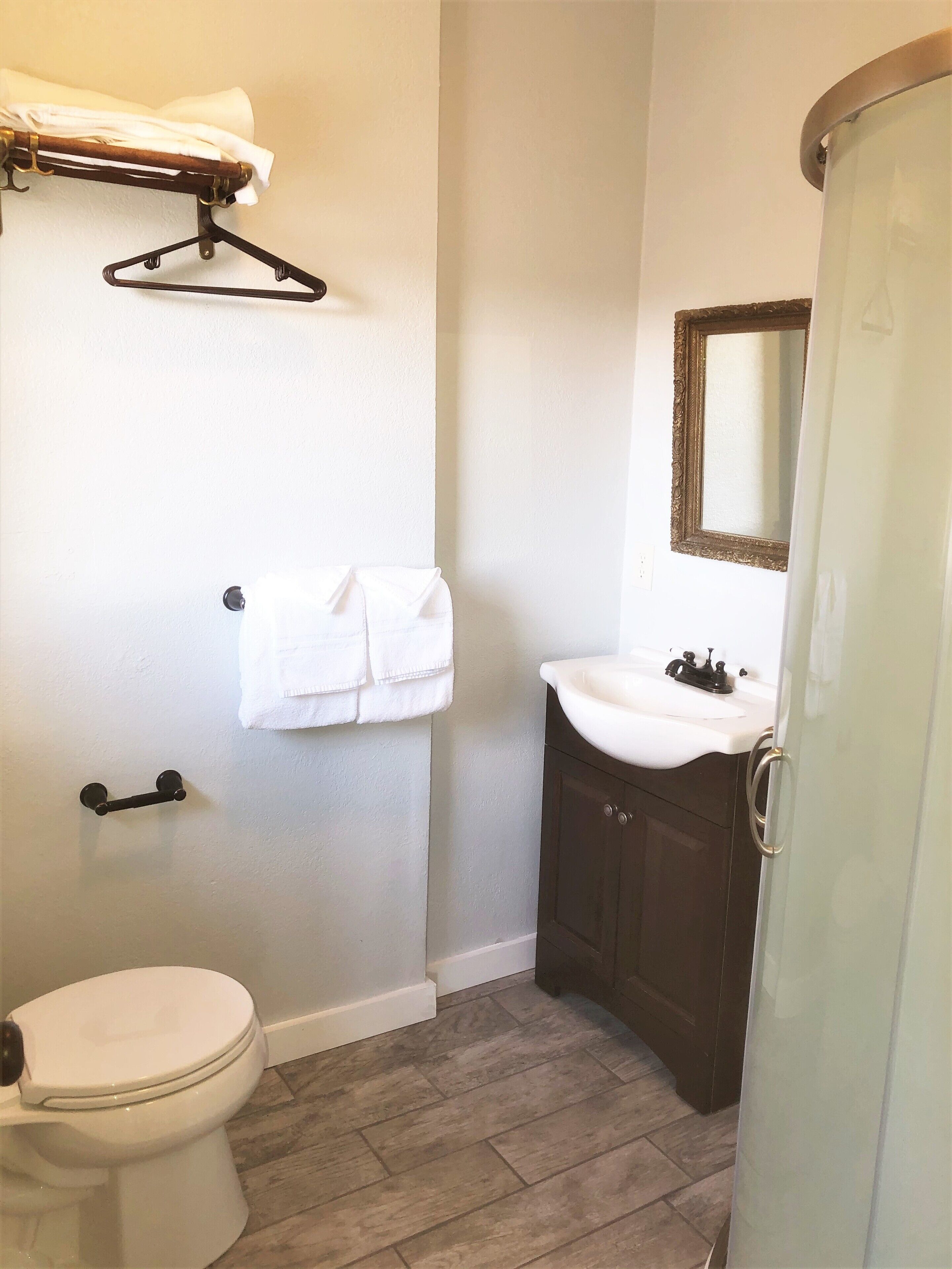 A bathroom with a toilet, a sink, a mirror, and a towel rack.