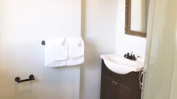 A bathroom with a toilet, a sink, a mirror, and a towel rack.