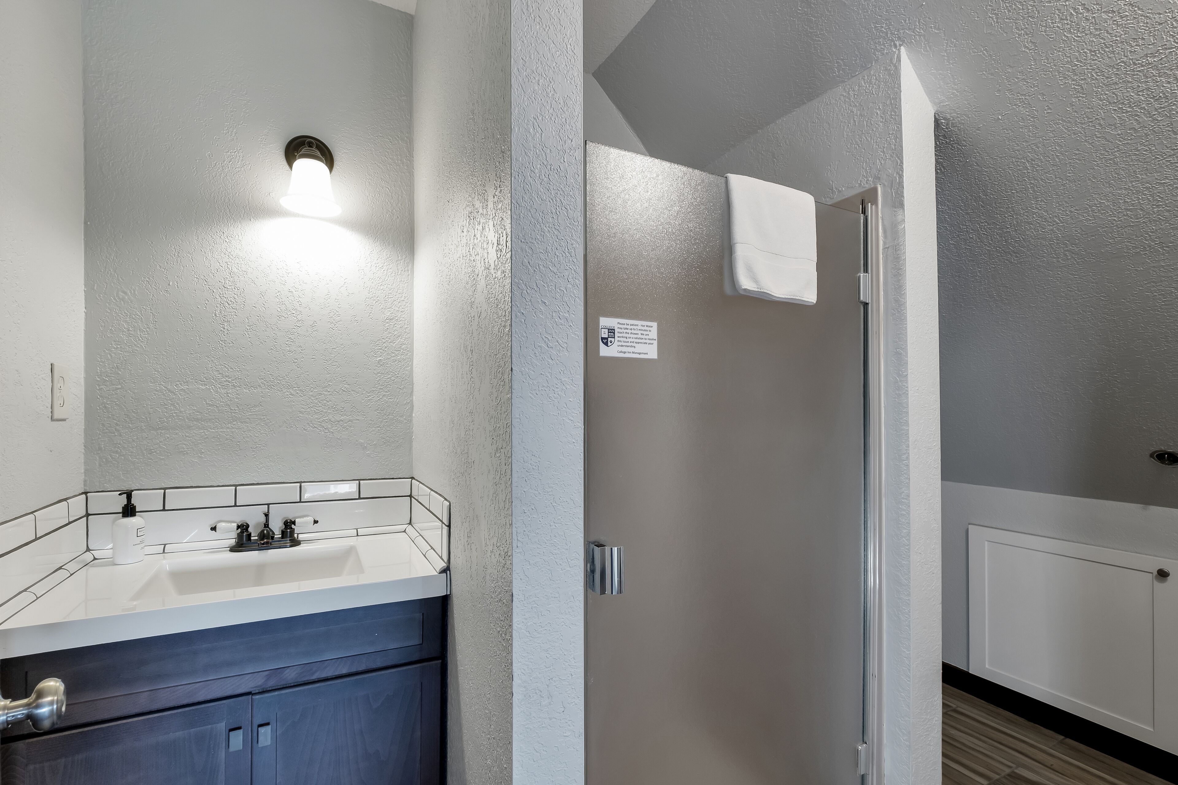 A bathroom with a white sink, a mirror, and a towel hanging on the wall.