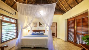 A room with a bed under a white canopy, wooden shutters, and a plant on a table. - Mayaland Hotel & Bungalows (Chichen Itza)