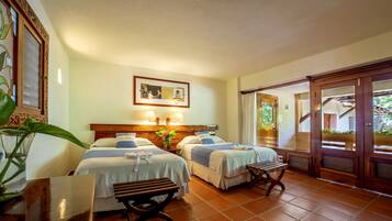 A hotel room with two beds, a wooden bench, a table, and a large window.