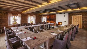 Ein großer Konferenzraum mit Holztischen und -stühlen, einem Kamin und einer Steinwand.