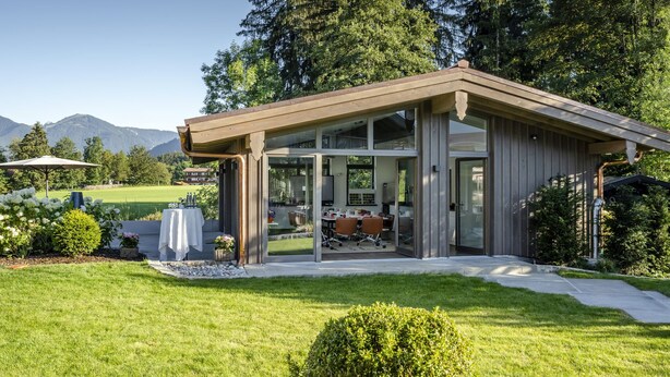Ein modernes Haus mit Terrasse, Essbereich und Bergblick.