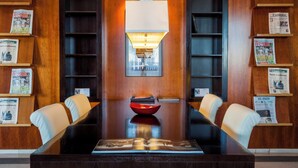 A conference room with a wooden table, two white chairs, a red bowl, and a wall-mounted lamp. - Sercotel AB Arganda (Arganda del Rey)