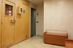 A wooden door with a window, a green door, and a tiled wall with a small sign.