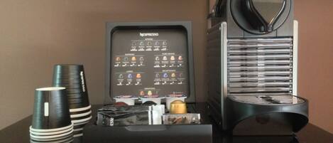 A coffee machine with a menu, disposable cups, and a coffee grinder on a table.
