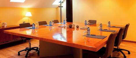 Un salón de conferencias con una larga mesa, sillas, botellas de agua y una lámpara.