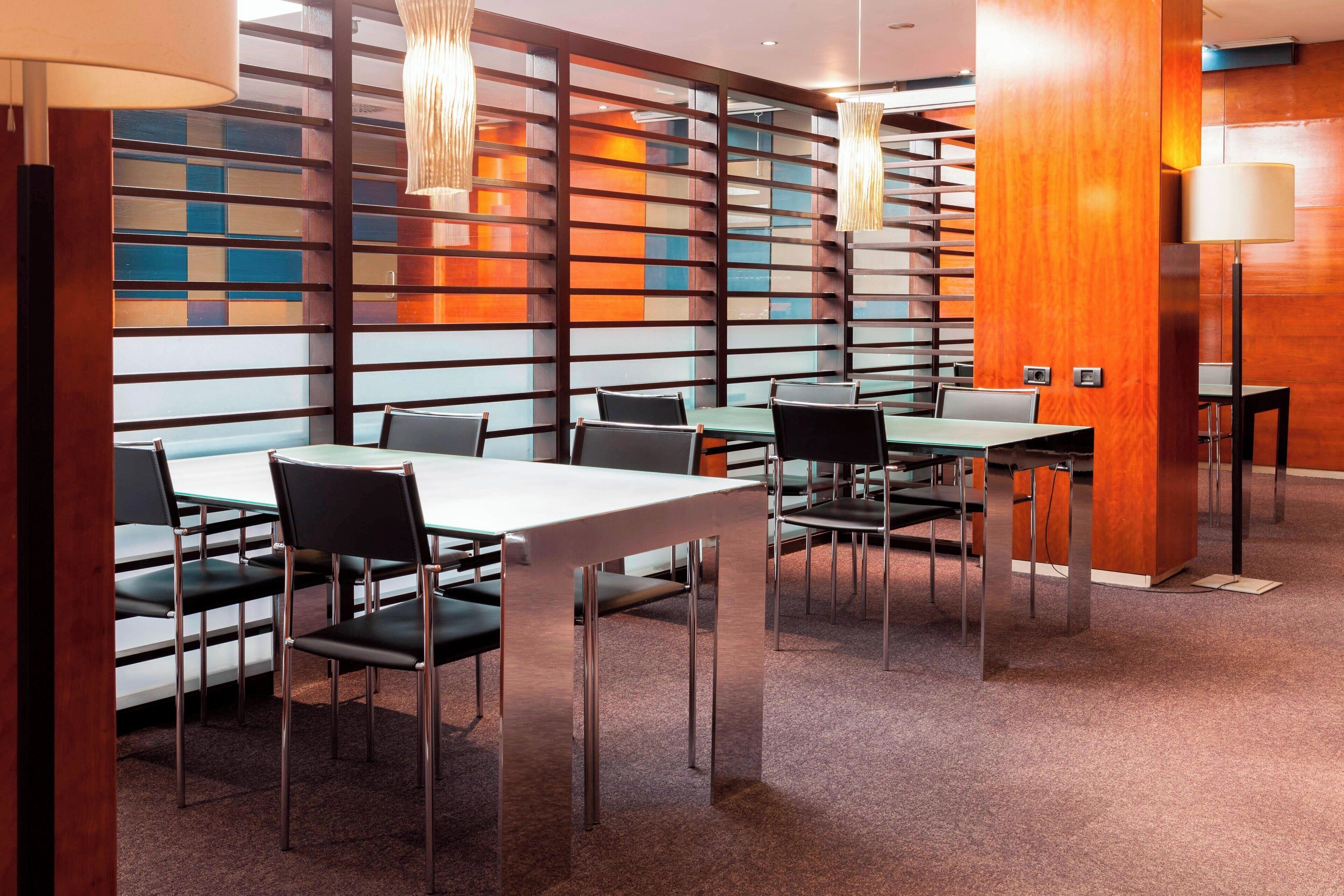 A modern conference room with glass partitions, metal chairs, and tables.