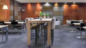 A modern conference room with a wooden table, chairs, and potted plants.