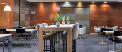 A modern conference room with a wooden table, chairs, and potted plants.