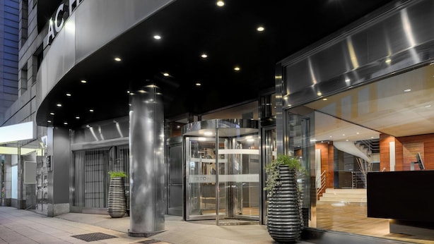 A modern hotel entrance with a revolving door, glass doors, and a reception desk.