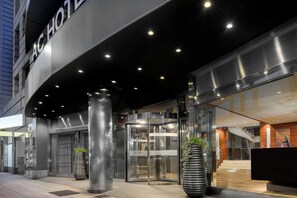 Una entrada de hotel moderna con puerta giratoria, puertas de vidrio y mostrador de recepción.