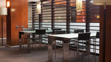 A modern conference room with a long table and chairs, wooden panel walls, and hanging pendant lights.