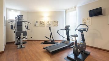 Un gimnasio con cinta de correr, elíptica y máquina de pesas.