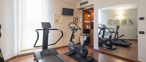 Un gimnasio en casa con cinta de correr, elíptica y bicicleta estática.