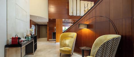 A modern lobby with a wooden wall, a staircase, and two armchairs.