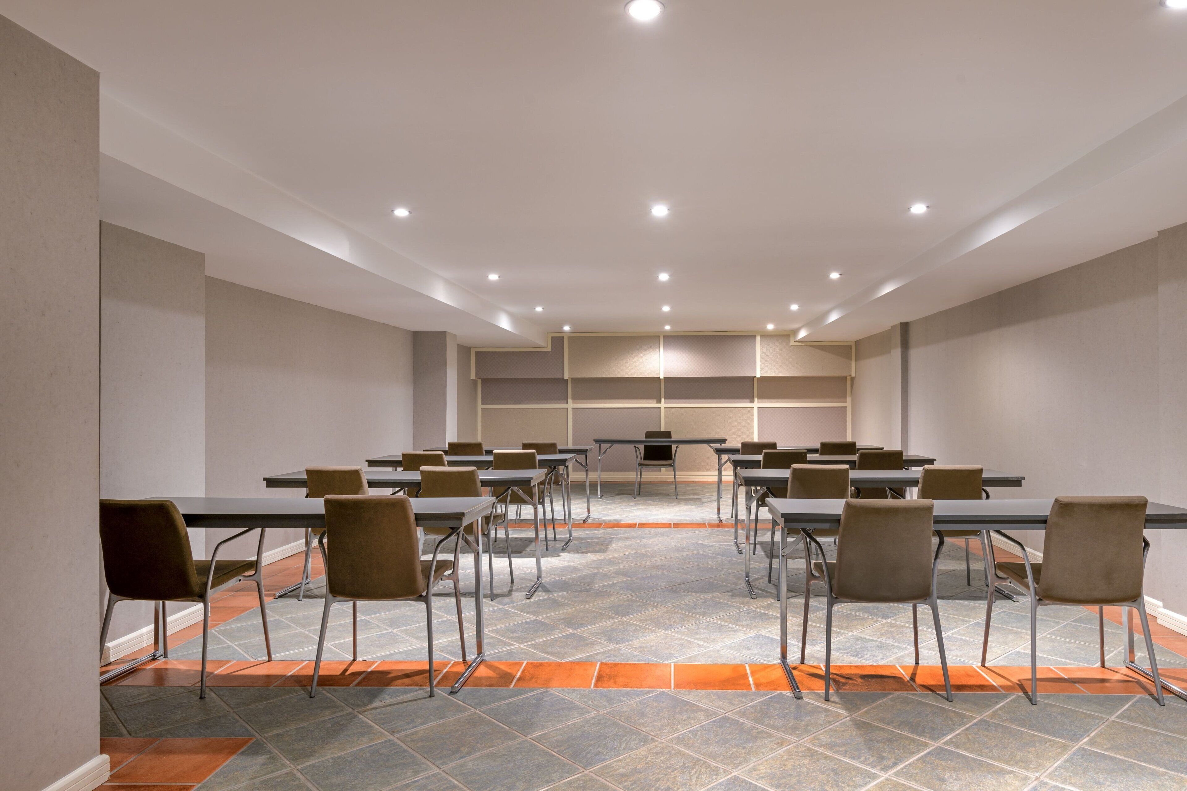 Sala de conferências com mesas e cadeiras dispostas para reuniões.