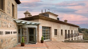 Un bâtiment doté d’une façade en pierre, d’une entrée en verre et d’un balcon agrémenté de balustrades.