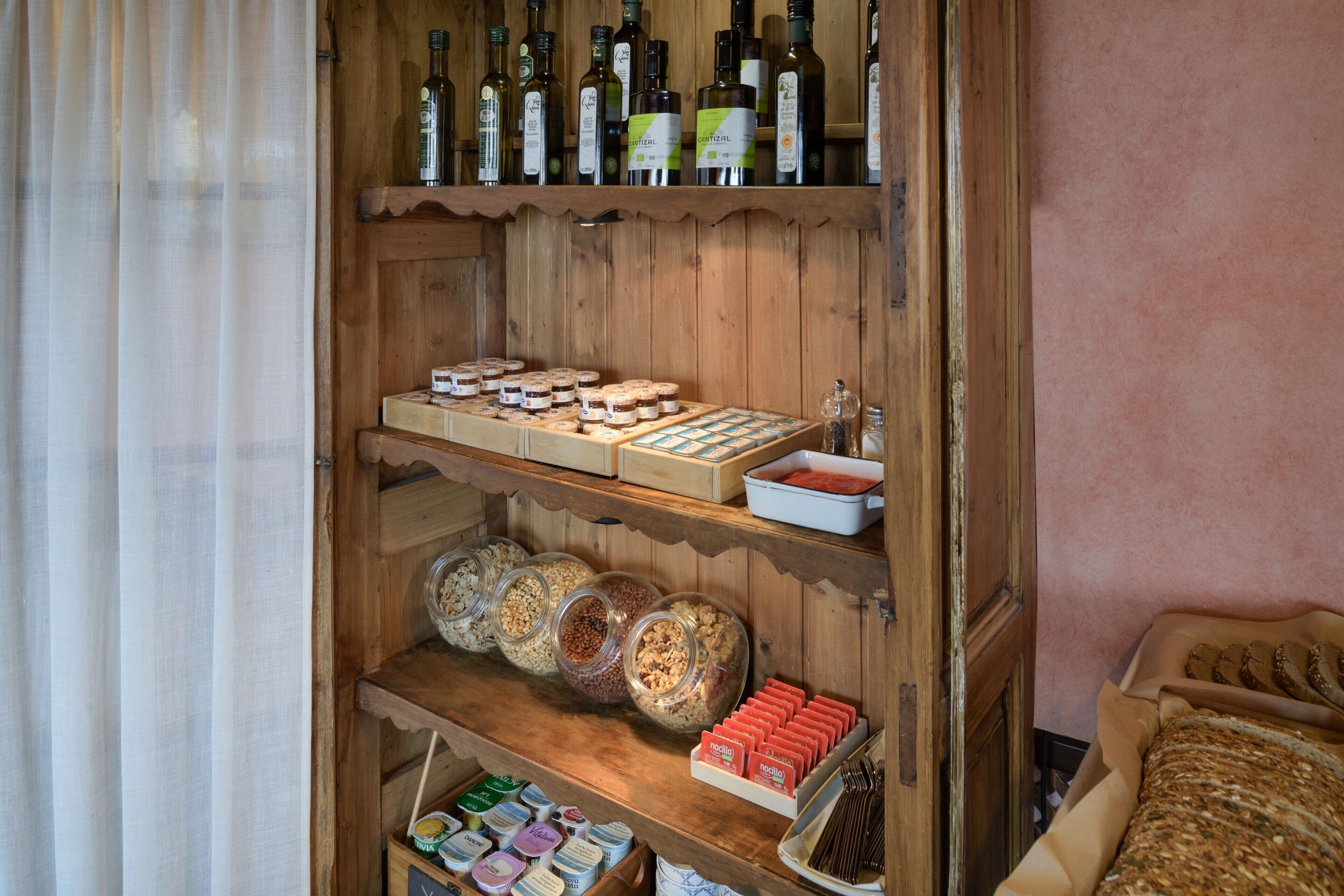 Un estante de madera con diversos alimentos y condimentos, incluyendo frascos de frutos secos y una variedad de productos envasados.