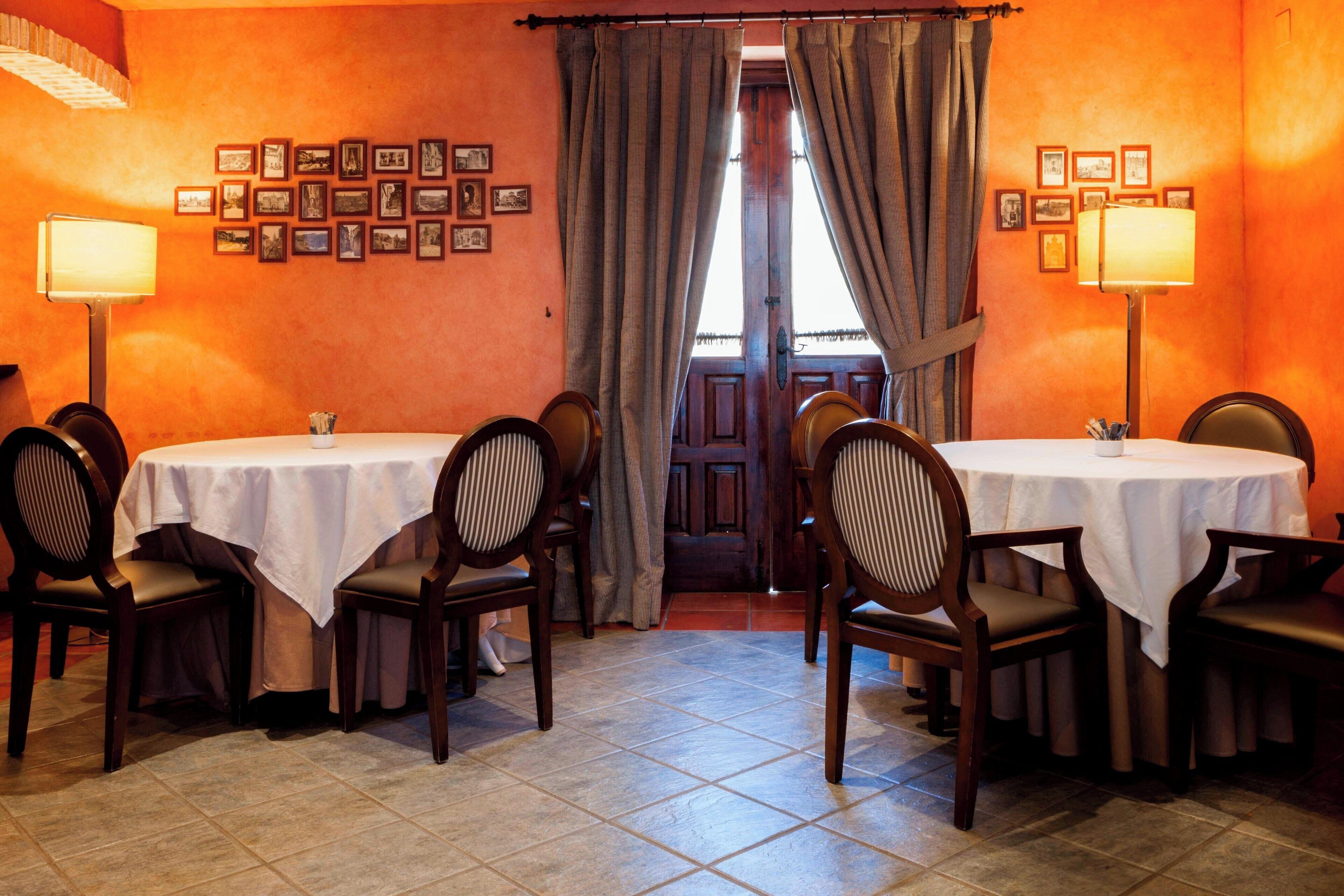 Un comedor con dos mesas, sillas y lámparas.