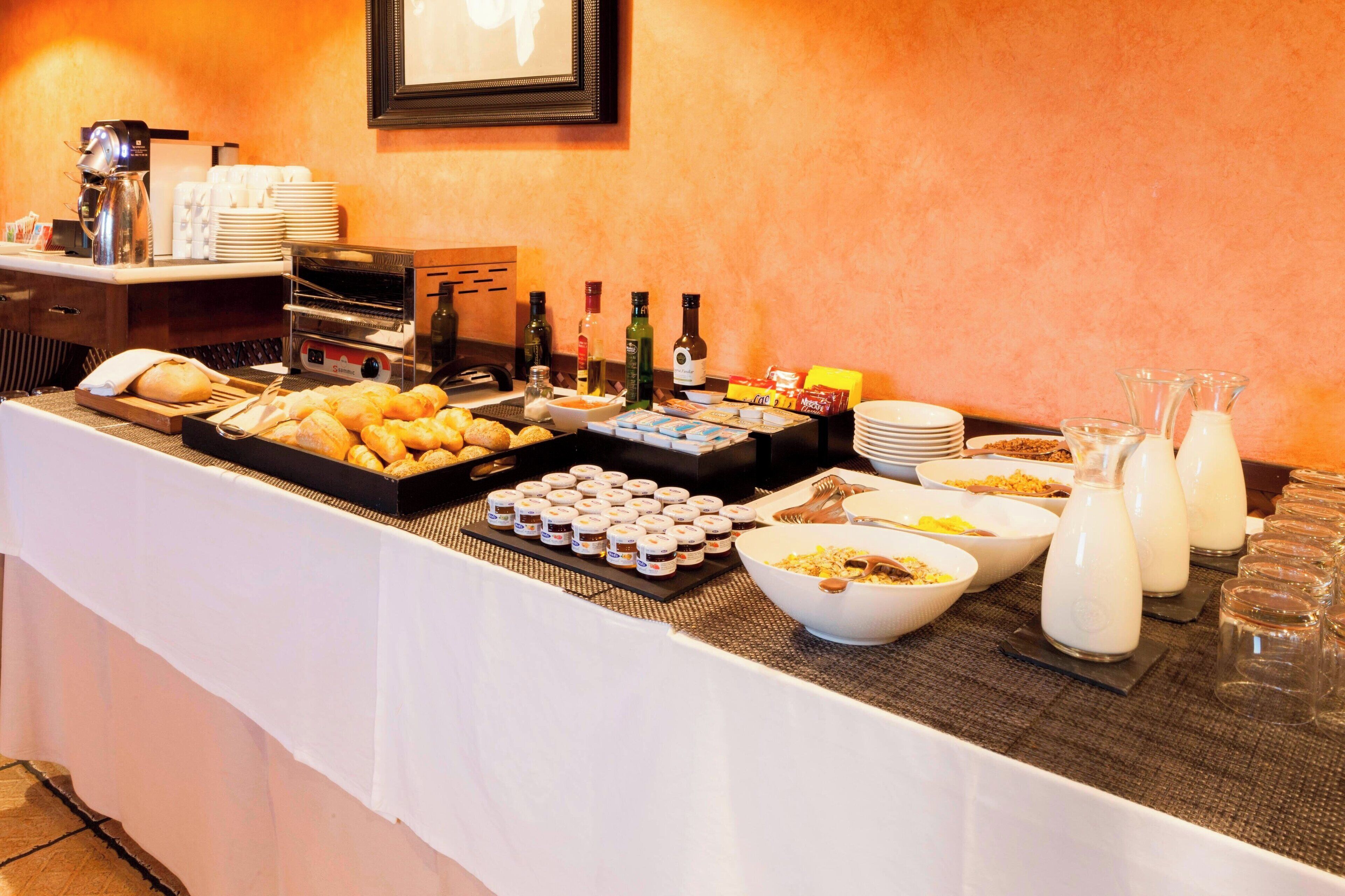 A buffet setup with various food items, condiments, and beverages.