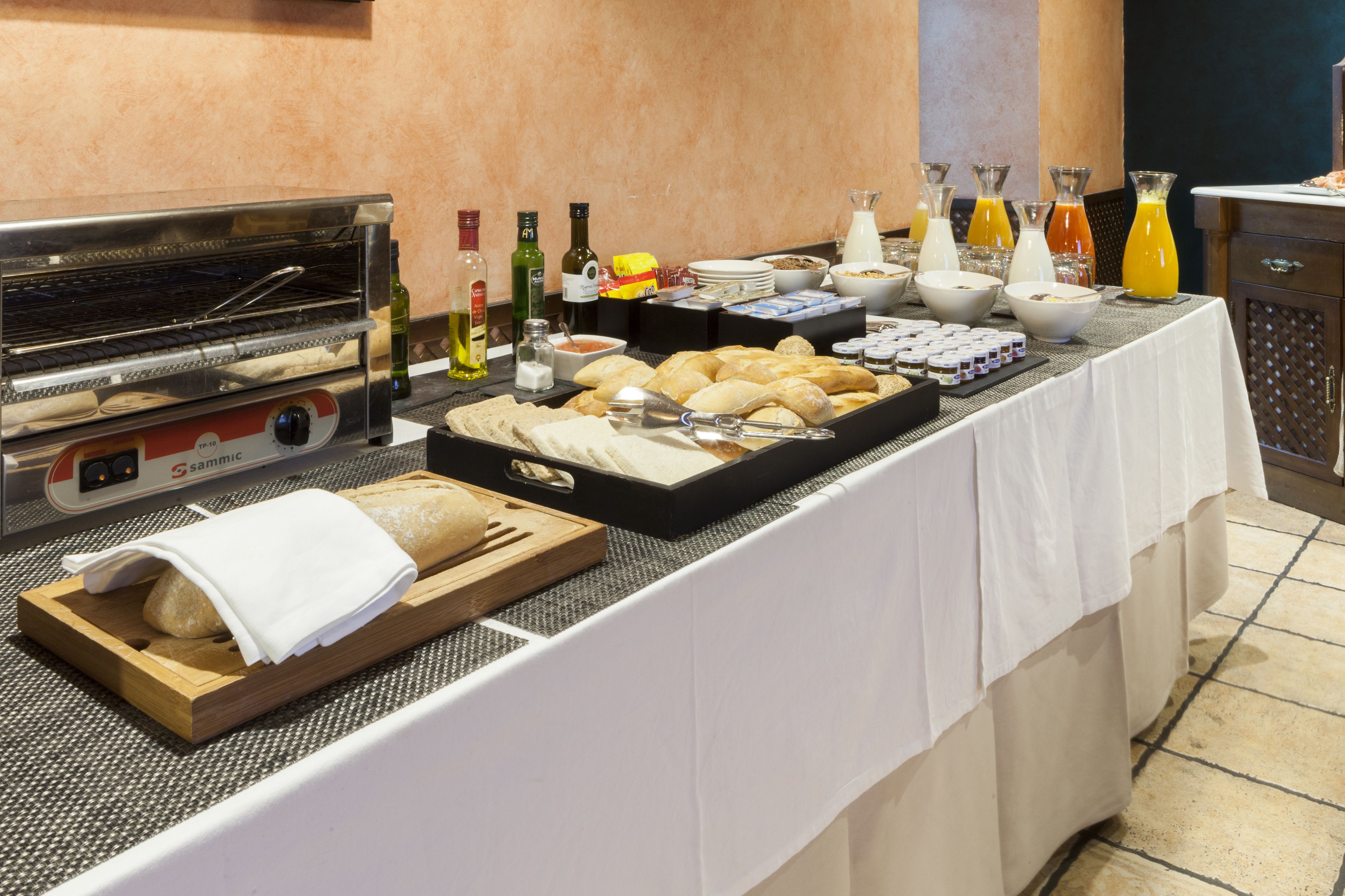 Montaje de bufé con horno tostador, pan, pasteles y diversas bebidas.