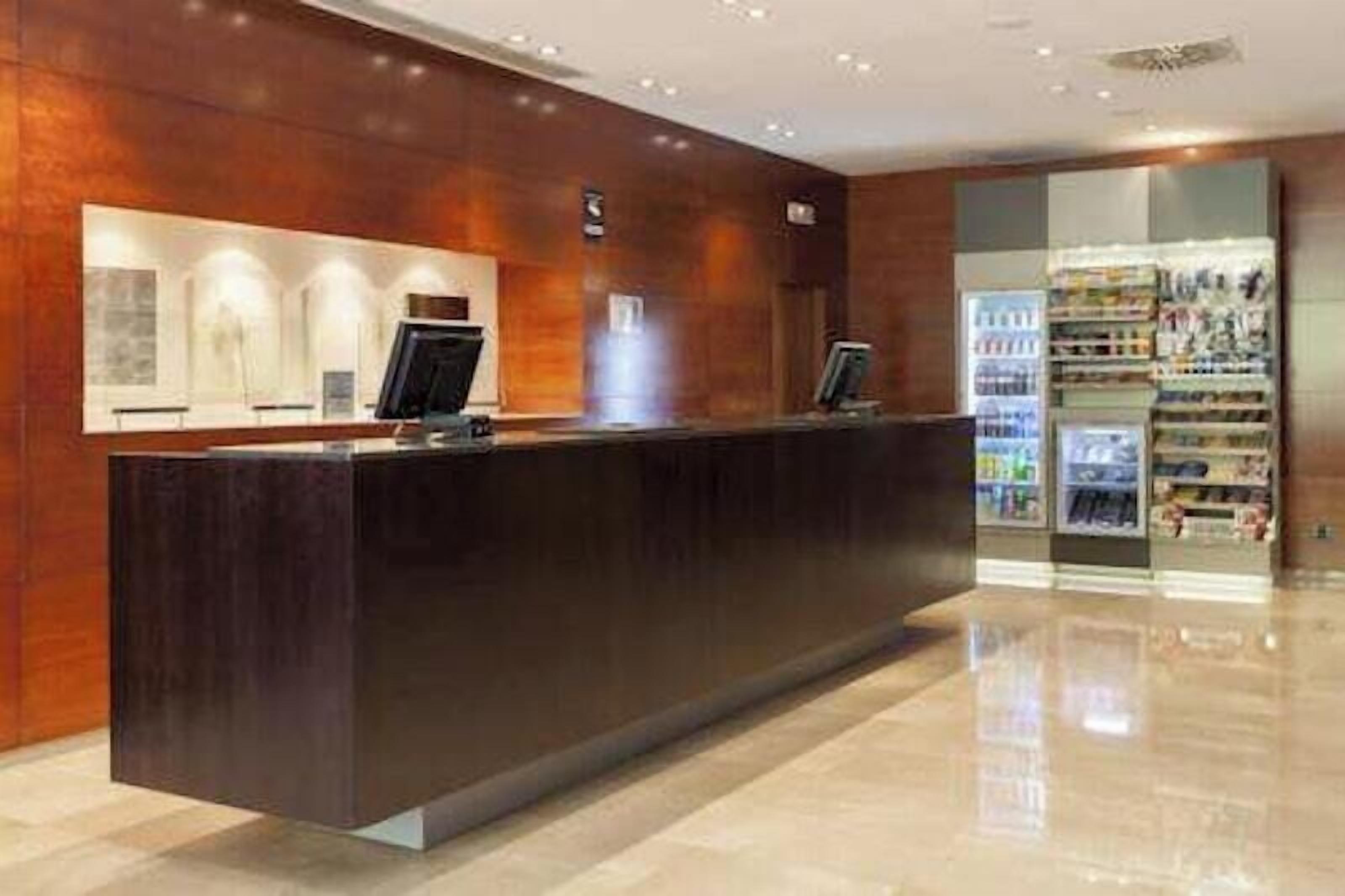 A reception desk with a digital screen, a counter, and a beverage dispenser.