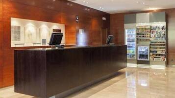 A reception desk with a digital screen, a counter, and a beverage dispenser.