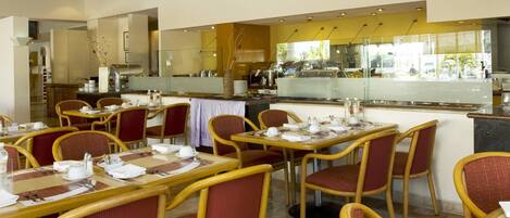 A restaurant with multiple tables and chairs, a kitchen area, and a view of the outside.