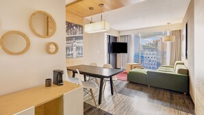 A modern hotel room with a dining area, a sofa, a TV, and a city view. - Fiesta Inn Insurgentes Viaducto (Mexico City)