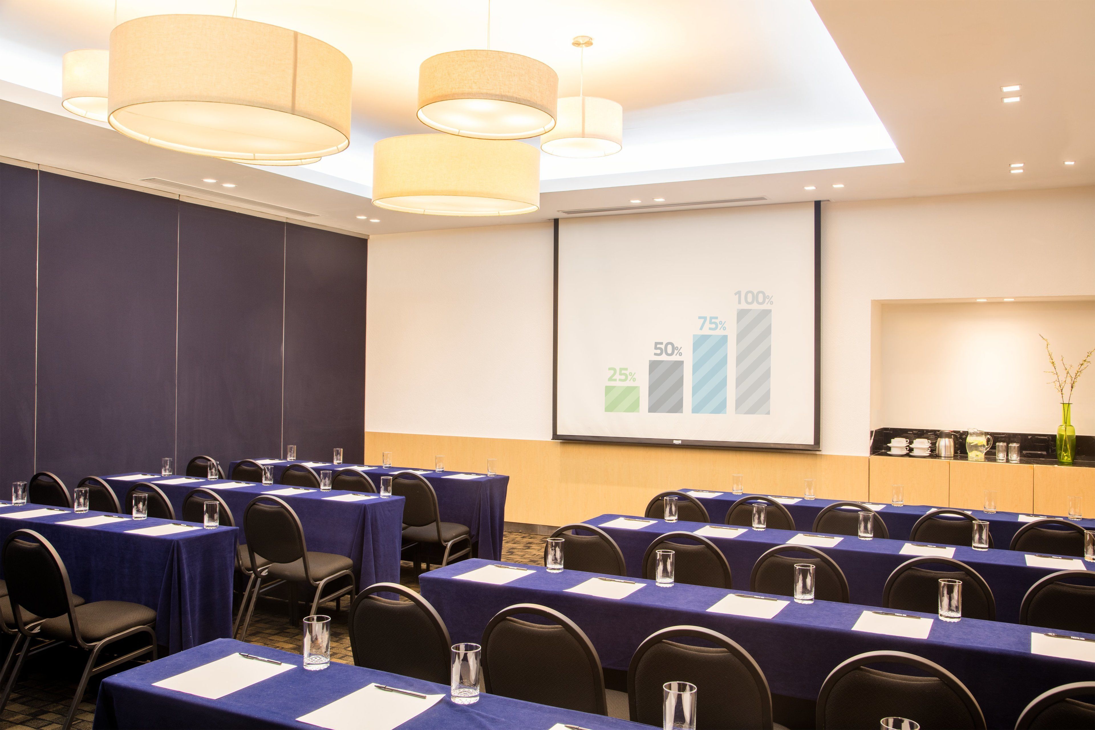 A conference room with tables, chairs, and a presentation screen.