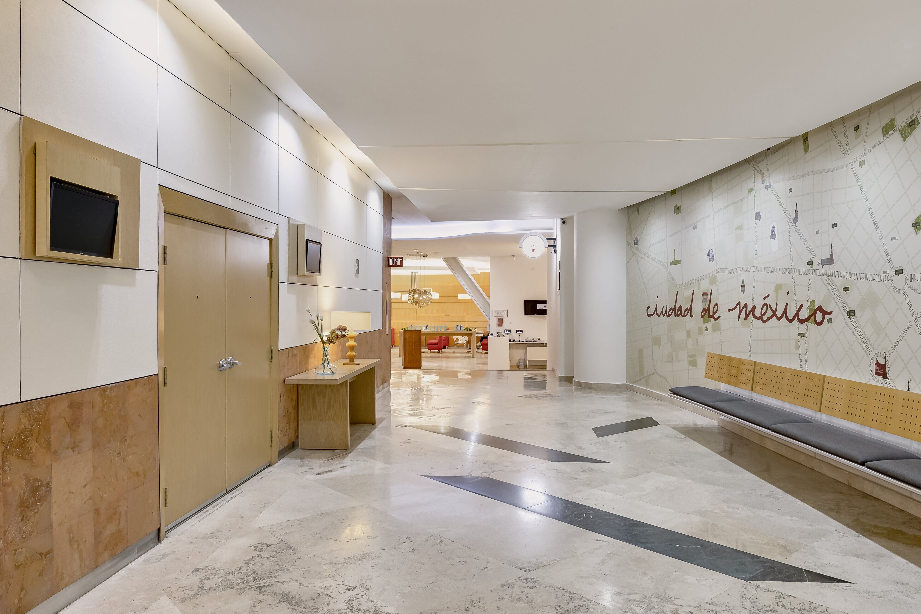 A modern hotel lobby with a marble floor, wooden lockers, a reception desk, and a wall with a map of Mexico.