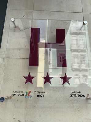 A glass plaque with a large 'H' and three stars, along with text indicating it is a tourism registration for Portugal, number 0971, valid until 27/3/2024. - Hotel do Chile (Lisbon)