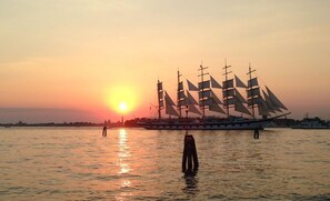 A large ship with multiple sails anchored in calm waters during sunset. - Russo Palace Hotel (Venice)