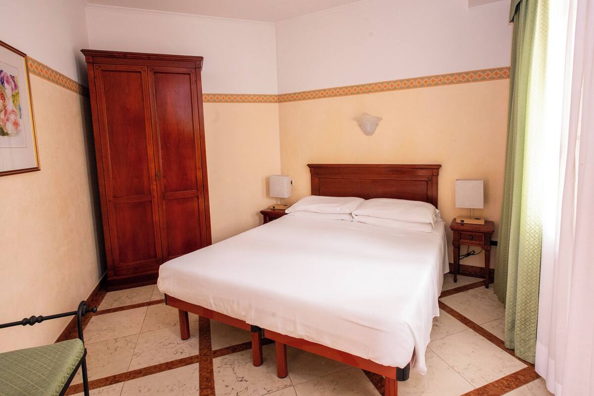 A bedroom with a bed, nightstands, a wardrobe, and a chair.