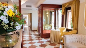 A checkered floor, a white sofa, a yellow armchair, a small round table, and a vase with flowers. - Russo Palace Hotel (Venice)