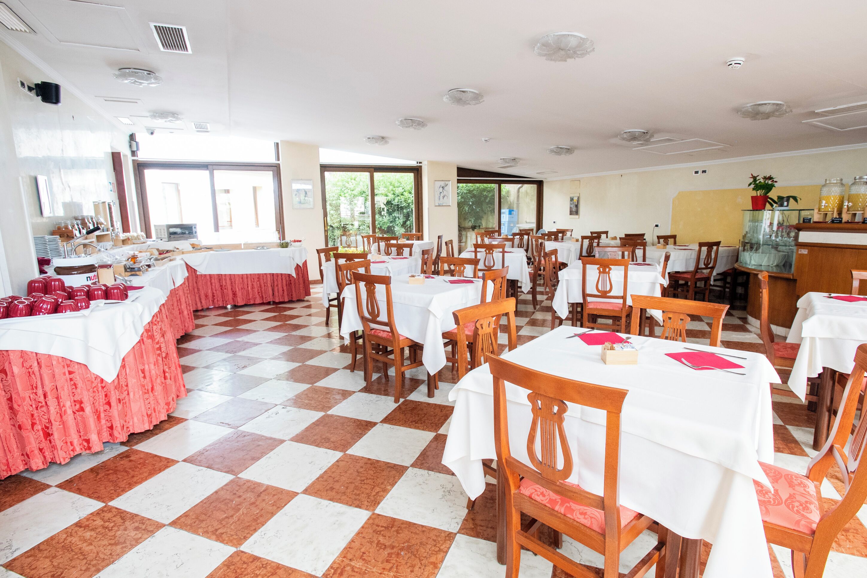 A dining area with multiple tables and chairs, large windows, and a checkered floor.