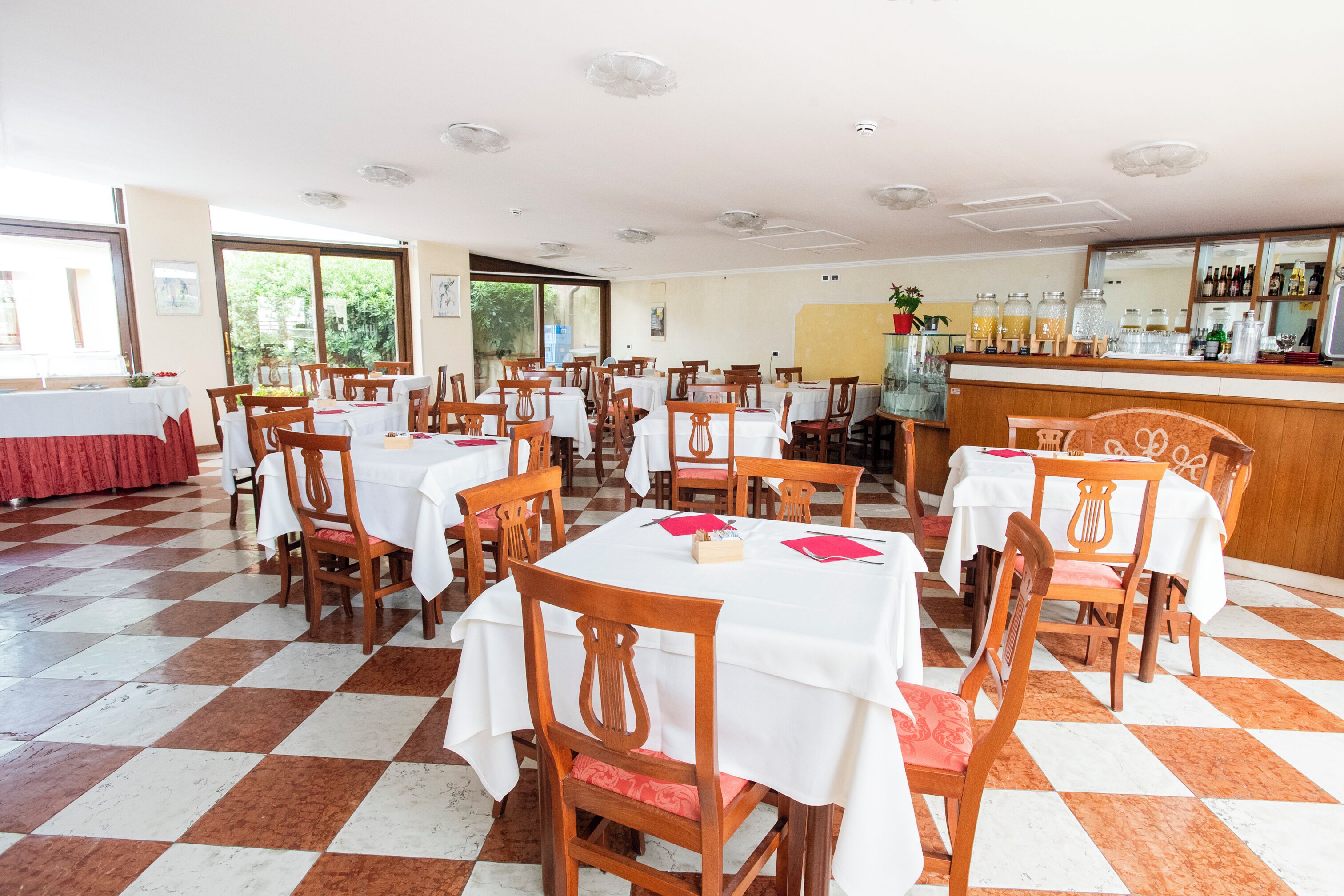 Un'area ristorazione con tavoli e sedie, una zona bar e ampie finestre.