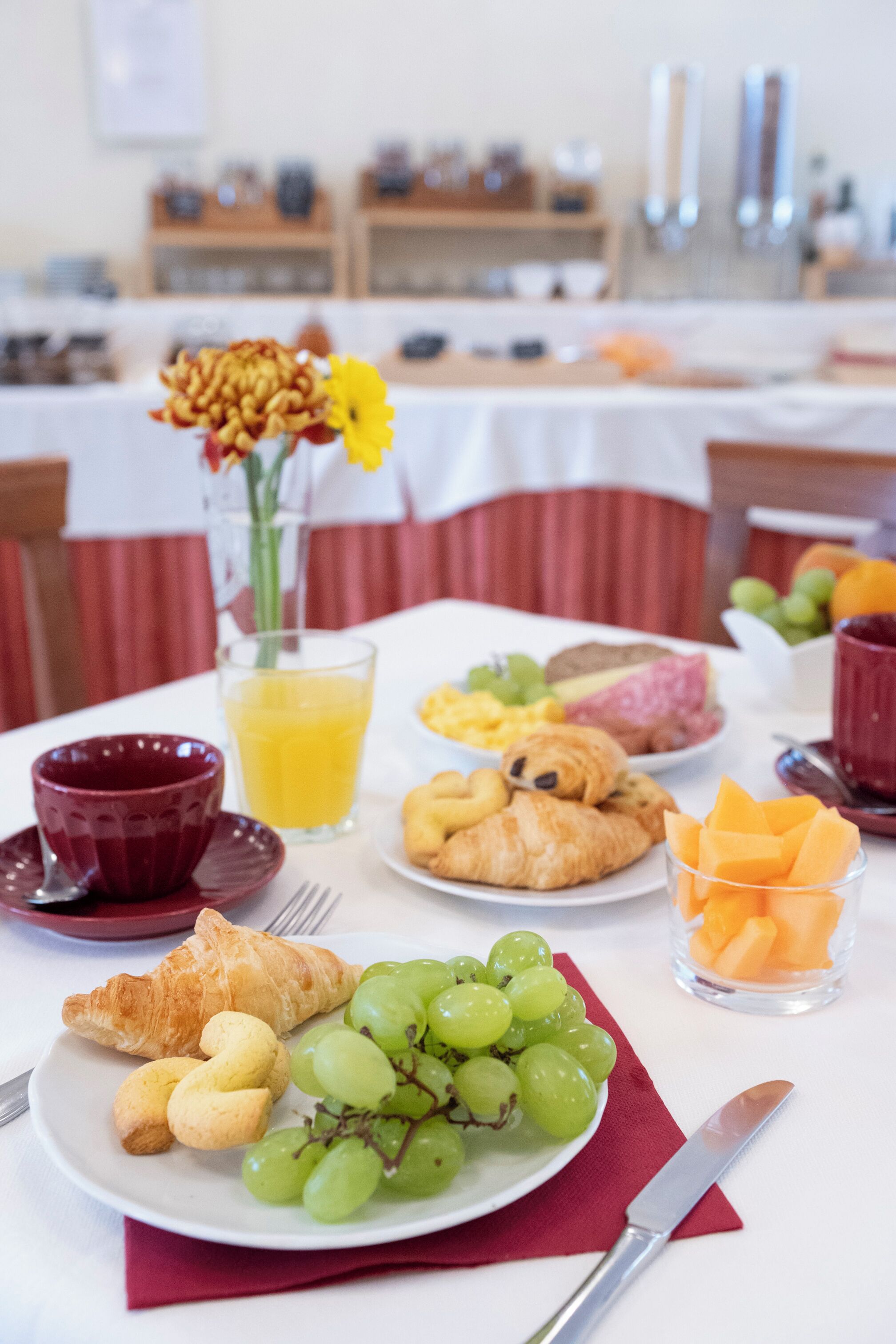 A breakfast table with croissants, grapes, and orange juice.