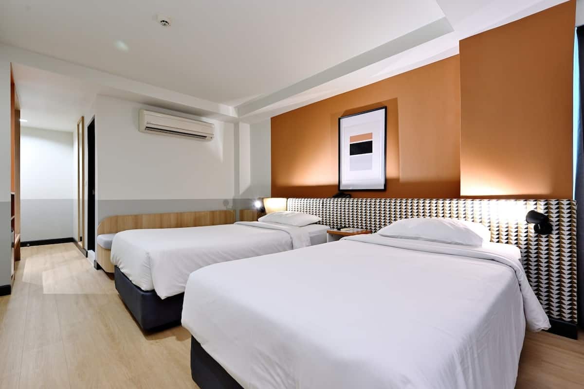 Une chambre d’hôtel avec deux lits, une grande fenêtre, un appareil de climatisation et un tableau encadré au mur.
